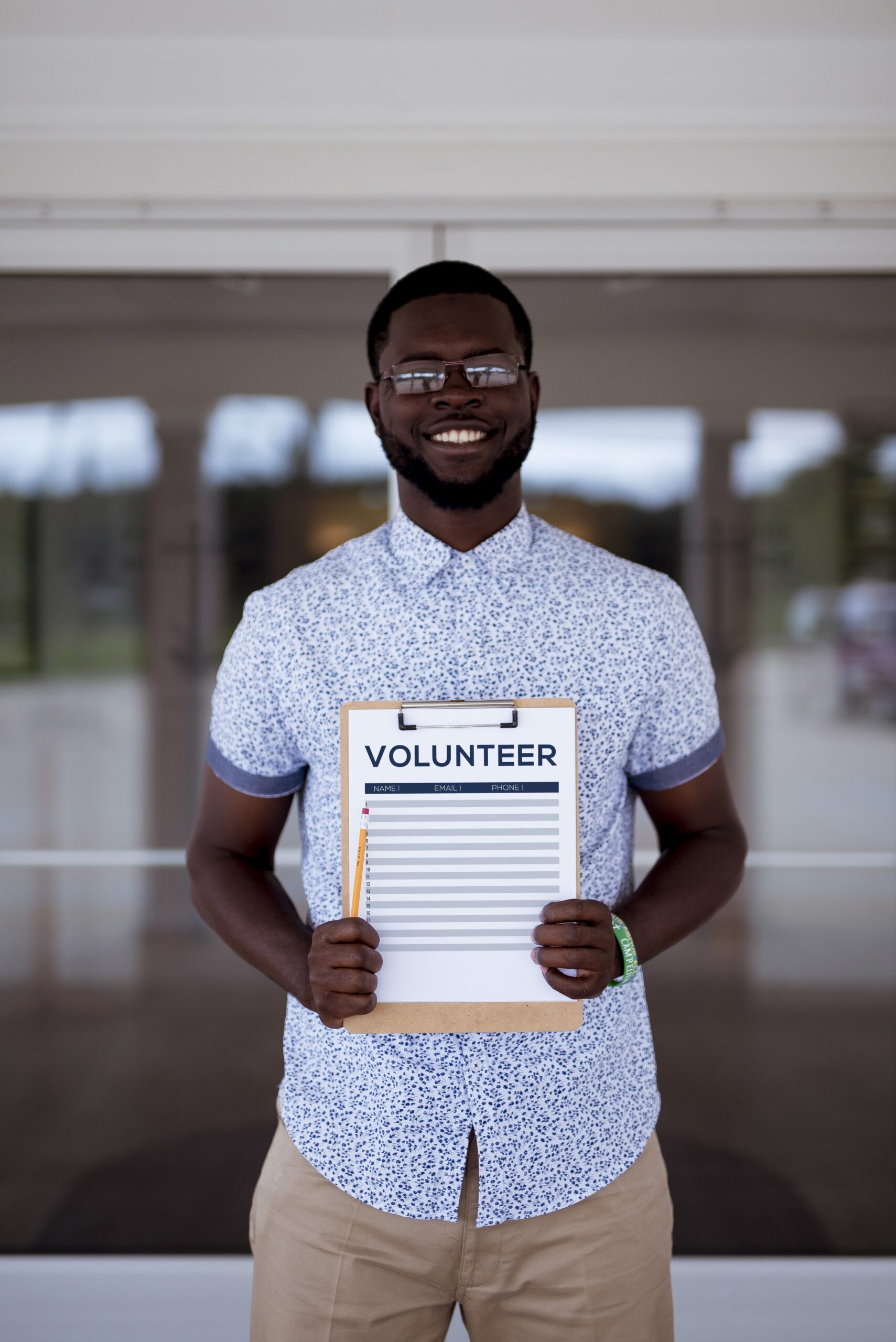 A vertical shot of a male holing a volunteer clipboard while smiling at the camera